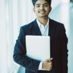 Portrait of indian happy businessman using laptop computer in office